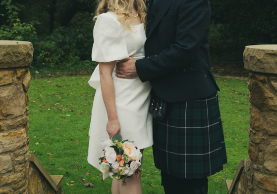 Autume wedding image, couple kissing outdoors, kilt, wedding dress, and flowers